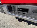 A close-up of the rear bumper and hitch area of a red 2018 GMC Canyon showing the hitch receiver and electrical plug connection