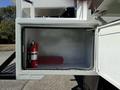 An open storage compartment on a 2010 International 4300 truck containing a red fire extinguisher and a toolbox