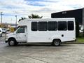 A white 2002 Ford Econoline van with a high roof and large windows is parked, showcasing its spacious design and extended length