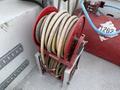 A red hose reel with multiple coiled hoses visible on a metal frame
