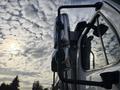 A 2013 Freightliner 114SD truck with a prominent side mirror reflecting the sky and clouds