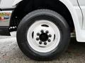 A close-up of a white wheel on a 2009 Ford Econoline featuring a metal rim with five lug nuts and a black tire with visible tread patterns