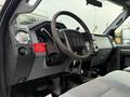 Interior view of a 2012 Ford F-550 showing the steering wheel dashboard and controls with a cup holder and grey seat upholstery