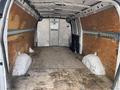 Interior of a 2023 GMC Savana van with plywood flooring and side panels lined with metal strips for securing cargo