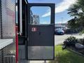 A metal door of a 1992 Emergency One Typhoon Superior fire truck is open revealing a black interior with a handle and a shiny diamond plate surface