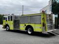 A 1995 Freightliner FLL086 fire truck in bright yellow with silver accents featuring hoses and a ladder on the side