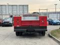 A red 2015 Chevrolet Silverado 3500HD pickup truck is parked with an open flatbed and mesh sides facing the viewer