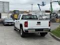 A white 2016 GMC Sierra 1500 pickup truck with chrome accents and a short bed is parked with its tailgate facing forward