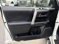 A close-up view of the driver's side door panel of a 2018 Toyota 4Runner featuring black leather and a silver handle with control buttons for windows