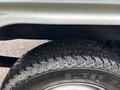 A close-up of a tire from a 2010 Suzuki Carry showing a rugged tread pattern and branding on the sidewall