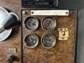 The dashboard of a 1996 Kenworth T800 displaying four gauges for fuel, oil pressure, and other indicators with a wooden texture background