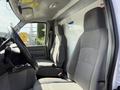Interior of a 2019 Ford Econoline showing two gray cloth seats in the front with a steering wheel and dashboard visible