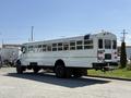 A white 2009 International 3000 CE school bus parked with numerous side windows and a rear loading door