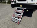 A metal boarding ladder with a textured surface and red safety markings extends from the back of a 2009 International 3000 CE bus
