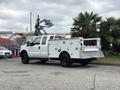 A white 2013 Ford F-250 SD work truck with a utility bed and black wheels parked on a concrete surface