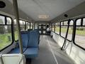 Interior of a 2002 Ford Econoline with blue seats and a spacious cabin featuring multiple windows and an overhead light