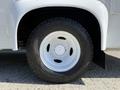 A close-up of the left front tire of a 2013 Ford Econoline with a white rim and black tread pattern visible