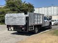 A 2019 Ford F-550 with a flatbed and metal sides positioned for cargo transport featuring a Tommy Gate lift in the back