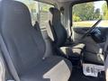 Interior of a 2020 Peterbilt 330 showing two black fabric seats and the steering wheel with a visible floor mat that reads Serving You