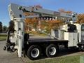 A 2011 International 7500 truck with a raised utility boom and extended outriggers designed for aerial work and maintenance tasks