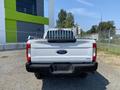 A 2017 Ford F-250 Super Duty truck viewed from the rear with a white exterior and a bed equipped with a ladder rack