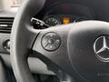 Steering wheel of a 2017 Mercedes-Benz Sprinter featuring a control button with directional arrows and the Mercedes-Benz logo