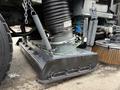 Close-up of the sweeping attachment of a 2009 UD Trucks UD 3300 featuring a large metal brush and a connected suction system with coils and chains