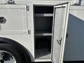 A 2005 Freightliner M2 106 with an open storage compartment revealing empty shelves and a small black crate inside