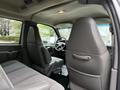 Interior view of a 2004 Chevrolet Express showing front seats dashboard and steering wheel with gray upholstery and a spacious cabin design
