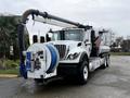 A 2013 International Workstar 7500 truck equipped with a large vacuum hose and reel in the front for waste management and cleaning tasks