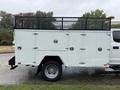 A white 2020 Ford F-550 with a tool body featuring multiple compartments and a black mesh rack on top