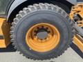 Close-up of a large rubber tire mounted on a rim painted orange featuring the brand name Alliance and deep tread patterns designed for heavy machinery use