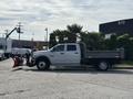 A white 2013 RAM 5500 truck with a flatbed and mounted snow plow attachment on the front