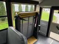 A wheelchair lift inside a 2014 Freightliner B2 bus with a safety mesh barrier and yellow support bars