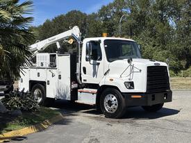 A white 2022 Freightliner 108SD truck with a working platform and utility equipment on the side