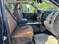 A 2015 RAM 1500 interior featuring leather seats in tan and black with a spacious cabin view and a central console with cup holders