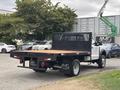 A 2023 Ford F-450 Super Duty with a flatbed truck design featuring a black rear panel and a wooden loading surface