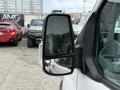 A close-up of the side mirror on a 2017 Ford Transit with raindrops on its surface displaying a reflection of nearby vehicles