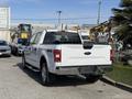 A white 2018 Ford F-150 pickup truck is parked with a view of its rear and side, showcasing the 4X4 badge and chrome accents