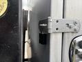 A close-up of the hinge and latch on the side door of a 2015 Mitsubishi Fuso FE160 truck showing metallic components and black latch detail