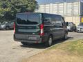 A 2016 Ford Transit 150 van is parked with a dark green and black exterior visible from the rear angle showcasing its large windows and spacious design