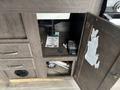 A cabinet with a dark wood finish is open to reveal plumbing underneath and a small safe inside, with a piece of paper lying on top