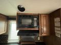 A microwave mounted in a kitchen cabinet with wooden doors and a black control panel