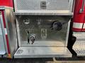 A metallic control panel featuring multiple dials levers and valves mounted on a fire truck with a textured surface and a red exterior