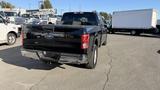 A black 2016 Ford F-150 pickup truck viewed from the rear with a chrome bumper and visible tow hitch