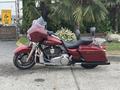 A 2009 Harley-Davidson Road King motorcycle in a deep red color with a large windshield and classic saddle seating
