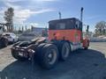 A 2009 Peterbilt Highway truck with an orange and black cab and a long chassis, featuring dual exhaust stacks and large rear wheels