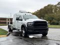 A 2024 RAM 5500 truck with a white exterior and a black grille parked on a wet road with a sleek cab design and prominent wheel wells