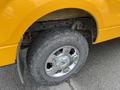 A close-up of the wheel and tire of a 2014 Ford F-150 with chrome rims and rugged tread patterns