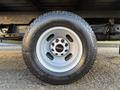 A close-up view of a 2015 GMC Savana wheel showcasing the silver alloy rim and a black tire with white lettering